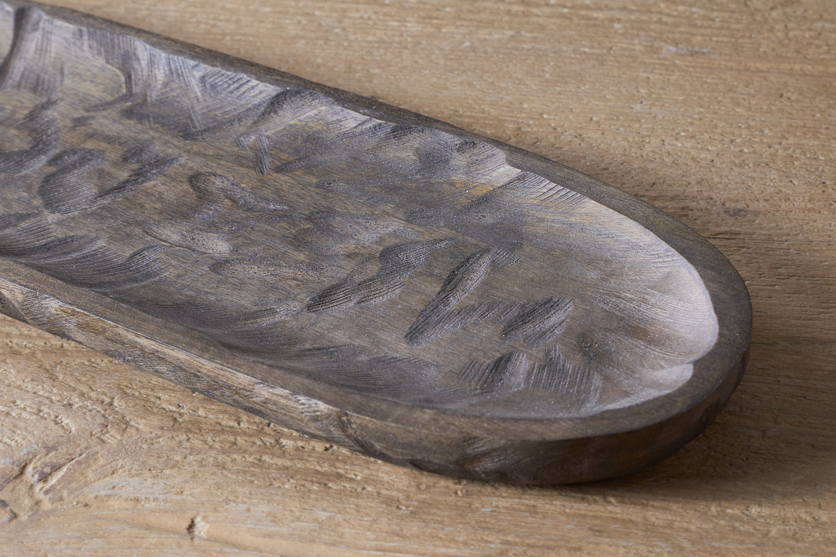 A close-up of the nkuku Nyati Serving Platter in dark brown, handcrafted from mango wood with textured grooves, resting on a light wooden surface—a stylish and sustainable home decor piece.