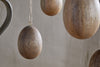 The nkuku Dima Mango Wood Hanging Egg Decoration – Natural (Set of 4) features smooth, brown mango wood eggs suspended on strings for a natural, minimalist Easter accent against textured beige walls.