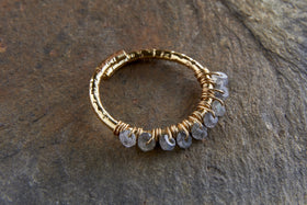 The nkuku Vani Labradorite Ring features a hammered gold-plated band with seven faceted labradorite stones wire-wrapped along one side, offering a rustic, handcrafted look with subtle sparkle.