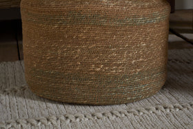 The nkuku Rana Tall Basket - Natural & Moss features subtle greenish threads and sits on a light gray, textured rug with raised lines, adding decorative storage atop wood flooring.