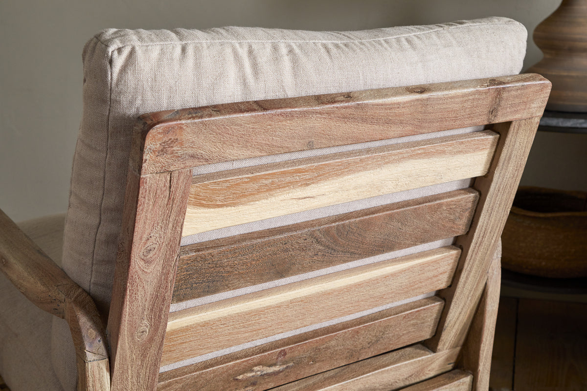 Close-up of the nkuku Jaya Acacia Wood & Linen Occasional Chair – Natural, highlighting its varied-tone horizontal acacia slats and light linen back cushion. The design creates a rustic, cozy atmosphere.
