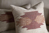 Two Kabir Wool Cushion Covers - Rust by nkuku, featuring geometric abstract brushstroke patterns in rust and brown tones, are displayed on a beige fabric sofa.