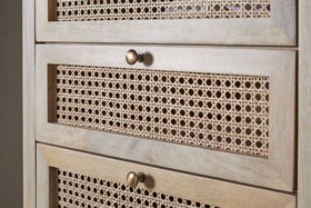 Close-up of the nkuku Kanz Mango Wood Tall Boy Chest of Drawers - Natural, featuring three cane-front drawers with round brass knobs. The light mango wood and detailed wickerwork lend a textured, airy feel.