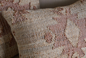 Close-up of two Nila Gul Cushion Covers by nkuku in earthy beige and rust, featuring woven geometric patterns and textured, raised stitching for a handcrafted, Indian-inspired look against a neutral background.