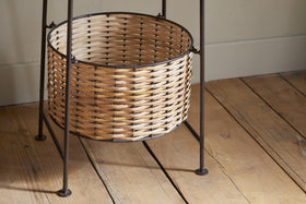 The Montali Iron & Rattan Three-Tiered Storage Stand by nkuku features handwoven natural rattan baskets with light and dark brown stripes on a black metal frame—perfect for stylish, practical kitchen or pantry organization.