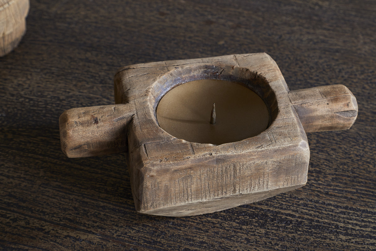 The nkuku Apu Reclaimed Wood Traditional Candle Holder - Natural features a rustic, square design with two side handles and a brown candle, showcasing weathered wood for a charming vintage look on your table.