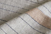 Close-up of the Buna Table Runner - Clay by nkuku, showcasing a light beige herringbone pattern with thin black stripes and a wide tan diagonal stripe. The visible fibers and natural stripes emphasize the runner’s tactile texture.