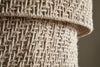 Close-up of two rolled pieces of coarse, natural beige burlap, displaying a rustic, geometric weave like the Thimba Woven Jute Chandelier by nkuku, with interlaced fibers reminiscent of its handcrafted texture under natural light.