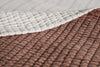 A close-up of two overlapping textured blankets: the top features a light fabric with thin wavy stripes, while the bottom is nkukus Nidra Velvet & Linen Bed Quilt in rust, showcasing soft cotton velvet and delicate Kantha quilting.