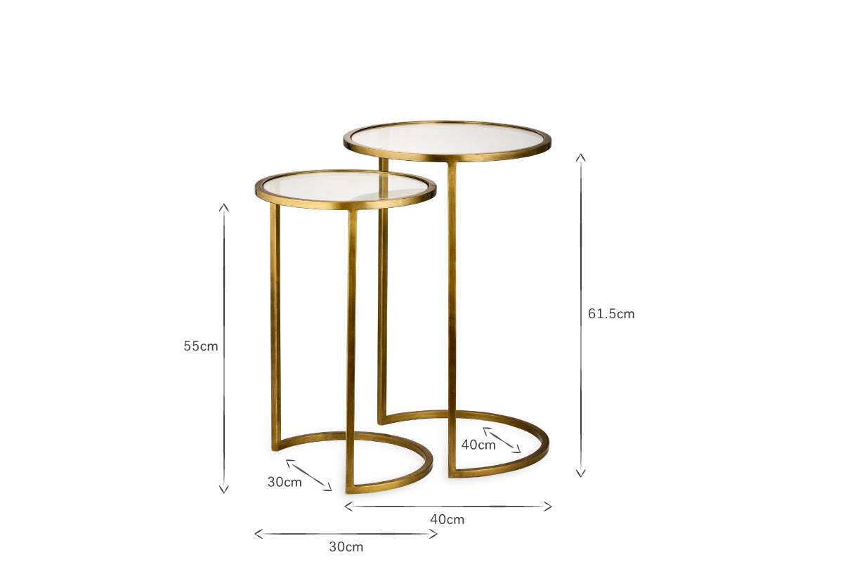 The nkuku Nakuru Iron & Glass Side Table Set - Brass includes two round nesting tables with glass tops and gold iron frames. Heights: 61.5cm and 55cm; base widths: 40cm and 30cm. Elegant and space-saving for any room.
