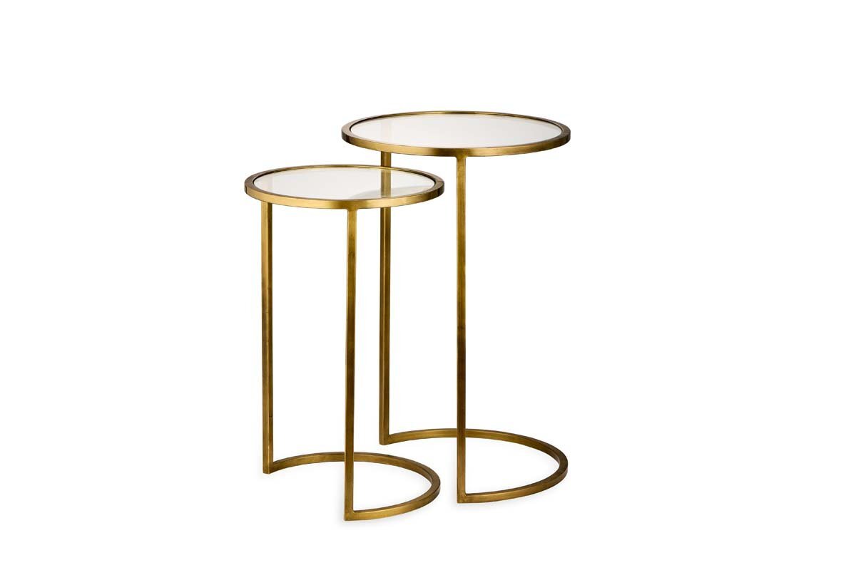 The Nakuru Iron & Glass Side Table Set by nkuku features two nesting tables with round glass tops and stylish brass C-shaped bases.