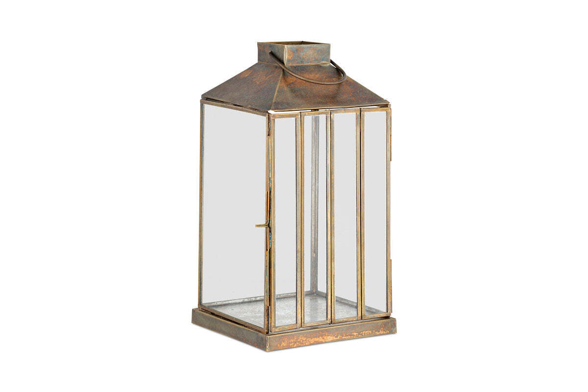 The nkuku Nampo Lantern - Aged Antique features clear glass panels, a weathered bronze frame, flat top, round handle, and a front hinged door for candles—ideal for vintage-style decor.