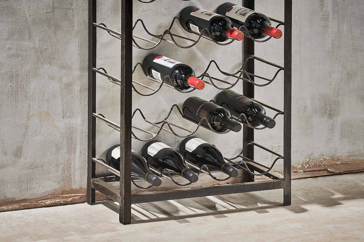 The nkuku Obra Industrial Wine Rack – Mango Wood & Iron (Large) holds 12 bottles in four rows, with dark brown iron and wood blending modern style and classic charm against a textured gray wall.