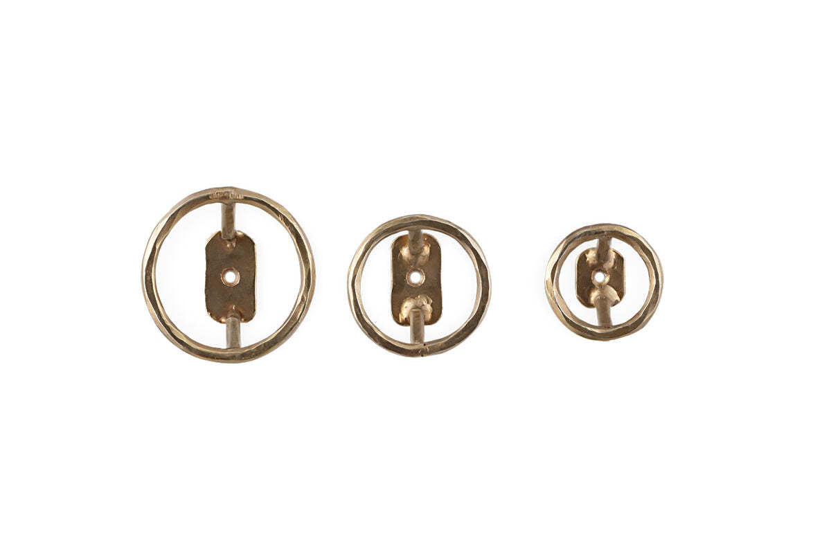 The Olani Bathroom Hooks by nkuku, in antique brass, come as a set of three. Each round hook features a central bar and prong for hanging and is displayed side by side against a white background.