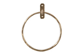 The Olani Towel Ring - Antique Brass by nkuku features a hammered brass finish and a rectangular wall plate with two screw holes, creating an elegant vertical towel holder perfect for any bathroom.
