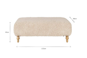 The Otas Teddy Ottoman - Off White by nkuku features fluffy, cream boucle upholstery, a solid mango wood base, and carved legs. Dimensions: 113cm W x 68cm D x 43cm H. A stylish blend of comfort and elegance for any space.