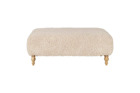 The nkuku Otas Teddy Ottoman - Off White is a rectangular boucle ottoman with rounded corners and four carved wooden legs, shown against a white background.