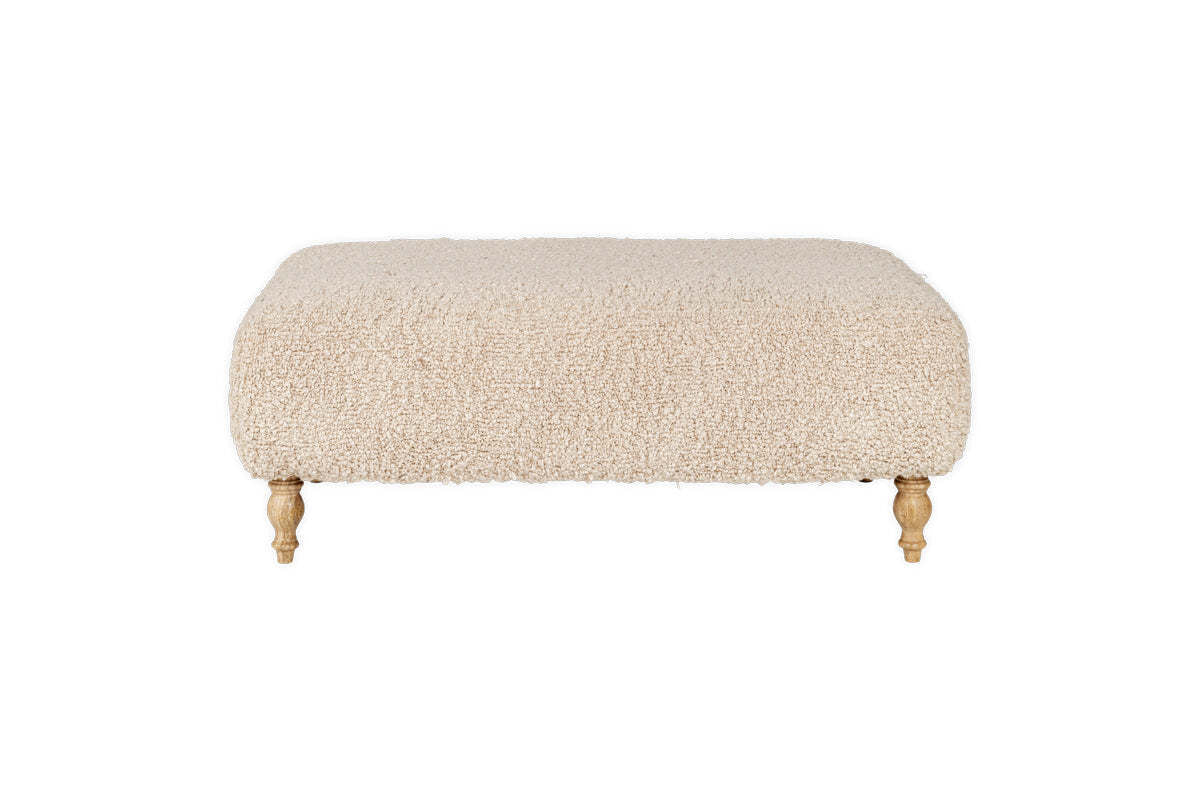The nkuku Otas Teddy Ottoman - Off White is a rectangular boucle ottoman with rounded corners and four carved wooden legs, shown against a white background.