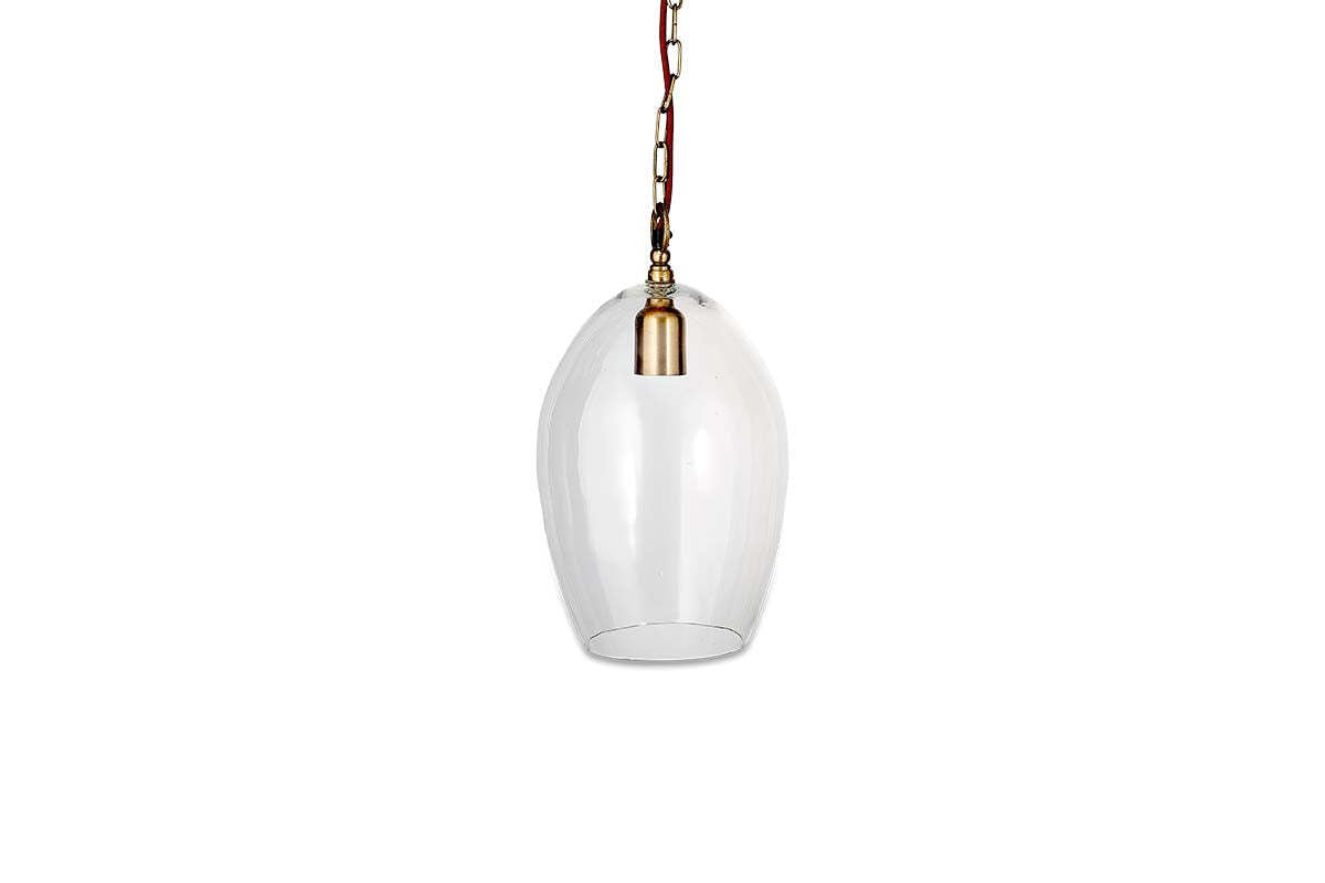 The nkuku Otoro Recycled Glass Pendant - Clear - Small Oval features an elongated clear shade, brass fittings, a brown cord, and hangs from a gold chain, creating an elegant look against a plain white background.
