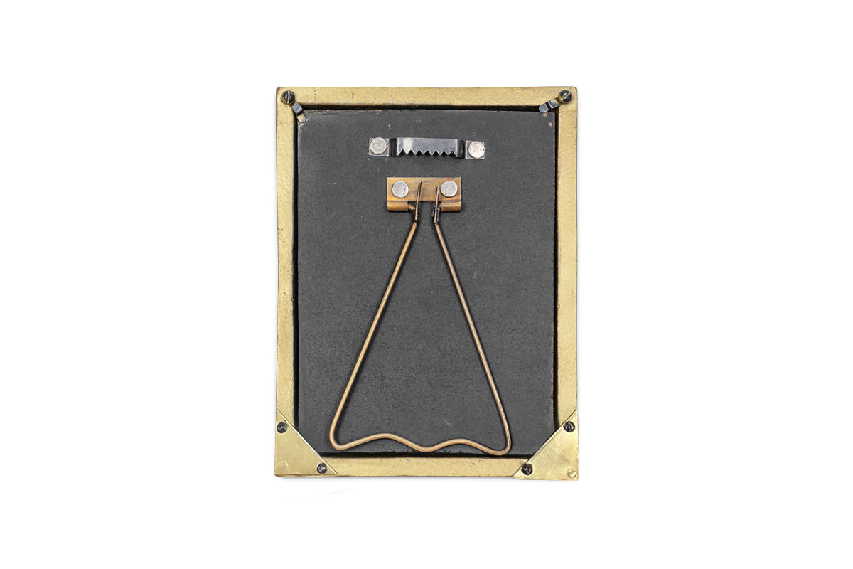 The nkuku Pambani Photo Frame - Antique Brass is a small rectangular frame featuring a brass border, metal corner protectors, a black back with a triangular stand, and a serrated hook for hanging. Photographed on a white background.