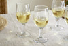 The nkuku Pani Wine Glass - Clear (Set of 4) features durable glassware, beautifully arranged on a light tablecloth in soft natural lighting—ideal for everyday dining.