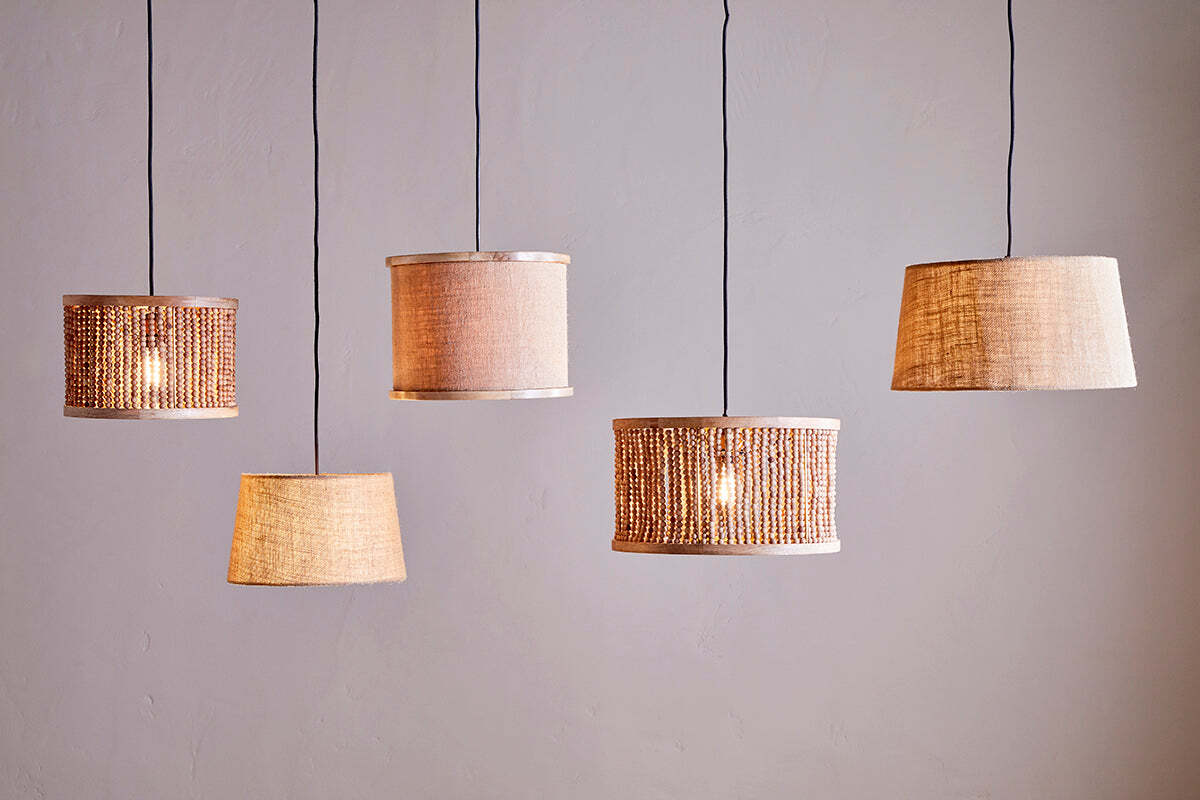 Five nkuku Dia Jute Lampshade - Natural pendant lamps hang against a plain, light wall. Each showcases unique woven or jute styles and shapes, adding warm ambient light and textured, cozy charm to modern décor.