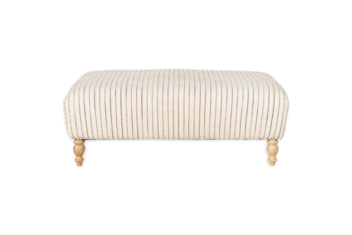 The nkuku Sanja Stripe Upholstered Ottoman in Off White features vertical black stripes on natural linen, four short turned wooden legs with a natural finish, and is showcased against a plain white backdrop for modern appeal.