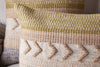 Close-up of the nkuku Tuleeka Wool Cushion Cover - Ochre, featuring a textured woven design with horizontal stripes, raised zigzag patterns, and tones of beige, tan, olive green, and ochre.