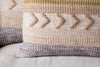 The Tuleeka Wool Cushion Cover - Ochre by nkuku features a textured woven design with geometric patterns in beige, gray, ochre, and olive green on a light background. Raised arrow shapes and stripes add depth to this decorative pillow.