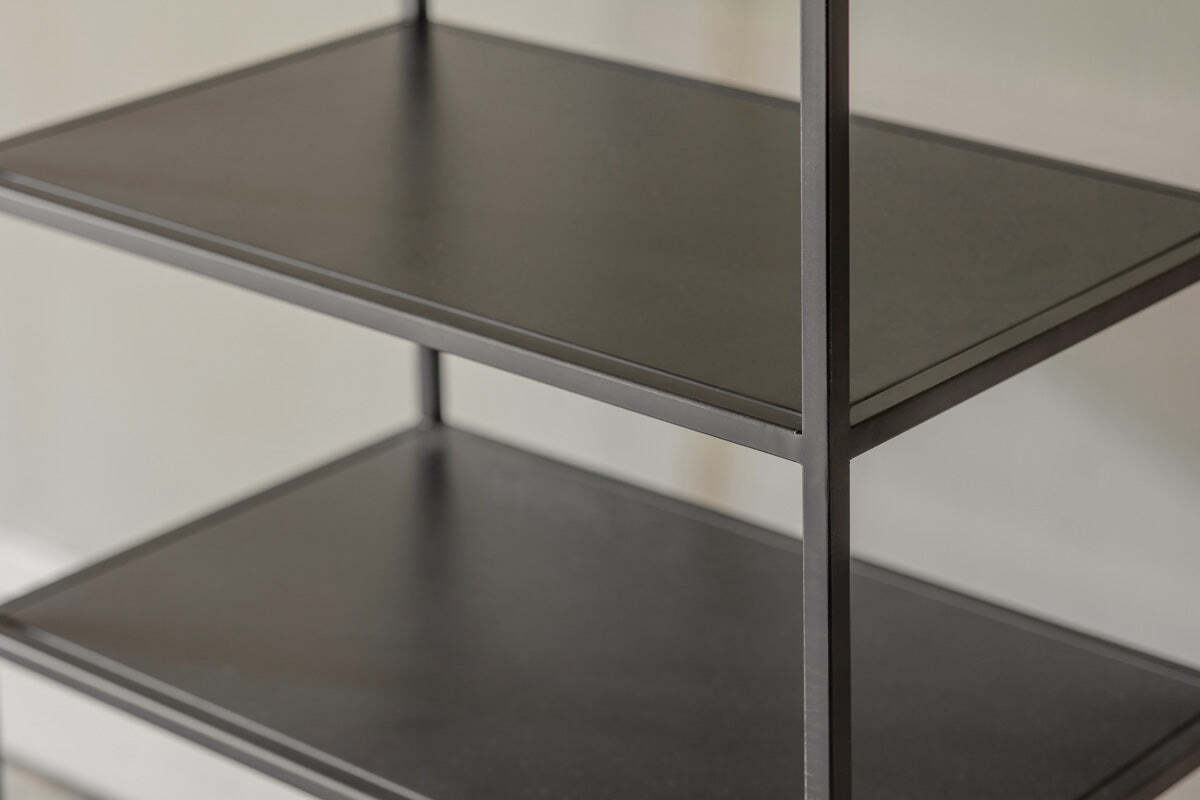 Close-up of the Tanvi Display Shelf by nkuku in black—a minimalist, narrow unit with three dark shelves and slim vertical supports against a light wall. Its matte surfaces are smooth, perfect for modern display.