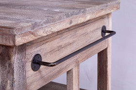 Close-up of the nkuku Tivu Reclaimed Wood Butchers Block - Natural, featuring a textured, weathered wood surface and a metal bar handle with round black brackets, set against a plain light wall.