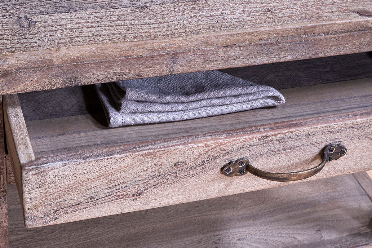 A close-up of the nkuku Tivu Reclaimed Wood Butchers Block - Natural shows an open drawer with a vintage metal handle and folded gray cloth, highlighting its rustic grain and farmhouse charm.