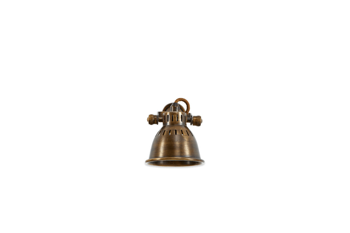 The nkuku Tubu Brass Spot Light in Antique Brass, featuring a dome-shaped vintage metal shade and visible side screws, is displayed centered against a plain white background.