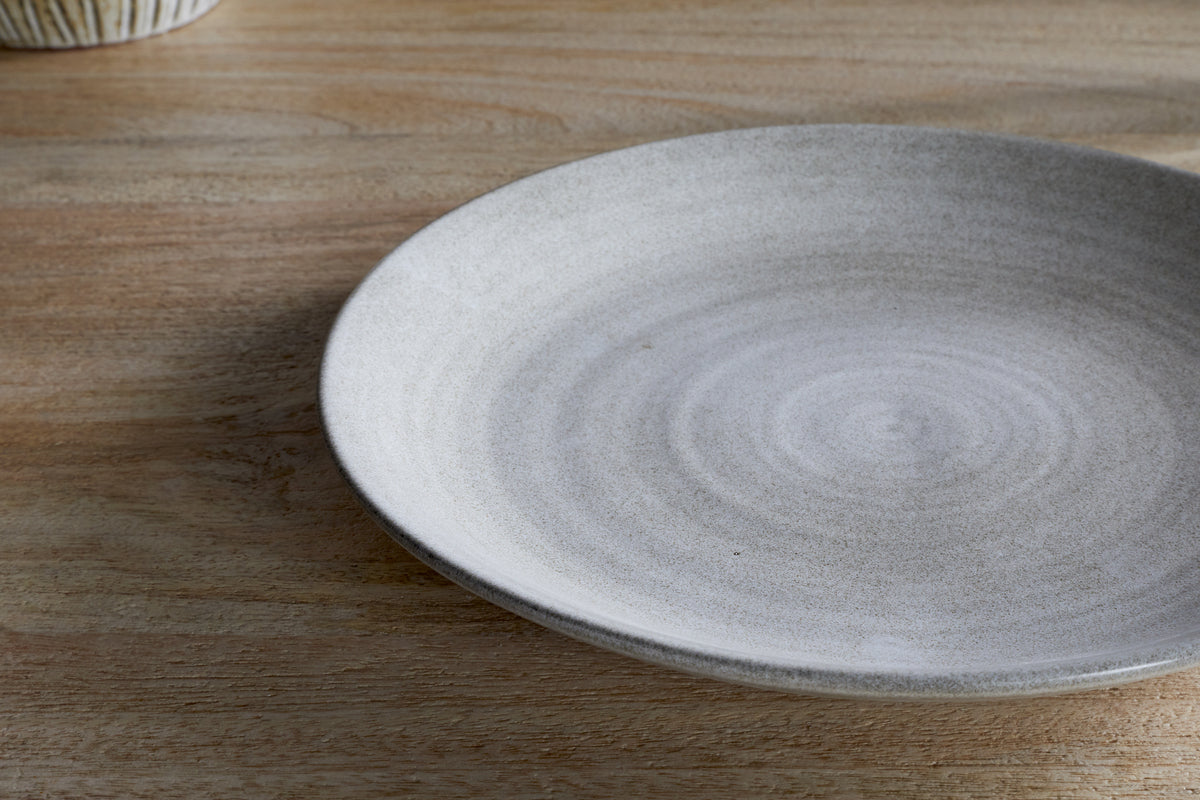 The nkuku Valinha Earthenware Dinner Plate in grey features a large, round design with a subtle concentric pattern and smooth matte finish, making it an elegant addition to your tableware collection.