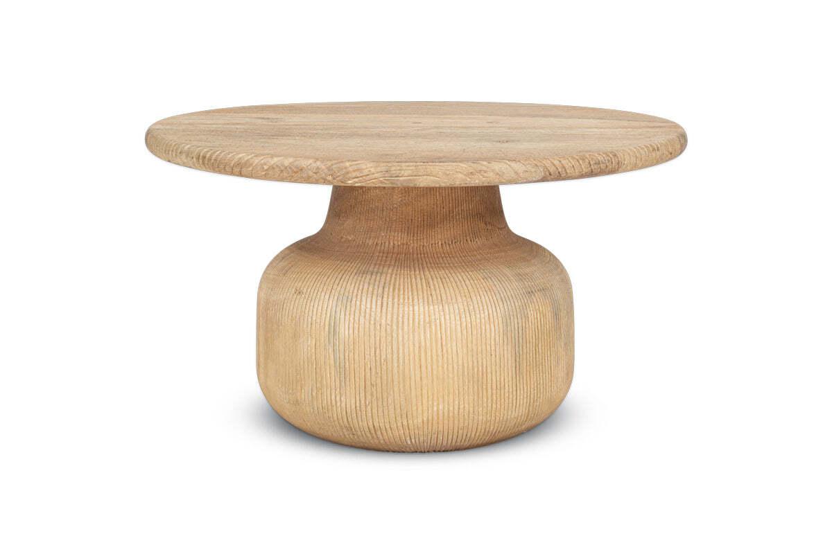 The nkuku Vivan Grooved Wood Coffee Table features a wide top and thick curved pedestal base in sustainable mango wood. With a light natural finish and visible grain, it offers contemporary style against a white background.