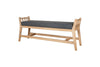 The nkuku Avanthi Upholstered Sleigh Bench in Charcoal features a carved wooden frame with angled legs, open slat sides, and a rectangular dark gray cushioned seat, shown against a white background.