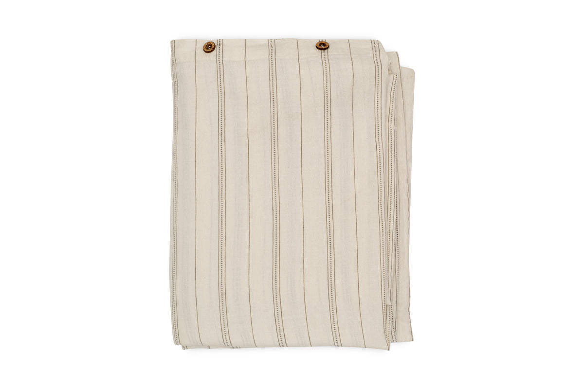 A neatly folded pair of beige pants with vertical thin brown stripes and two brown buttons at the waistband, echoing the natural sage green tones of the nkuku Anta Hemp & Cotton Duvet Cover.