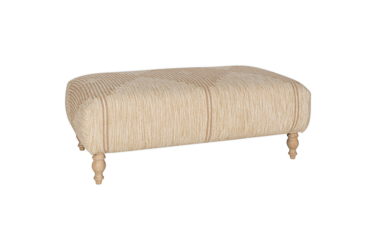 The Aranya Upholstered Ottoman - Natural by nkuku features textured beige cotton jute upholstery, a soft cushioned top, and four turned wooden legs—an elegant and versatile accent for your living room.