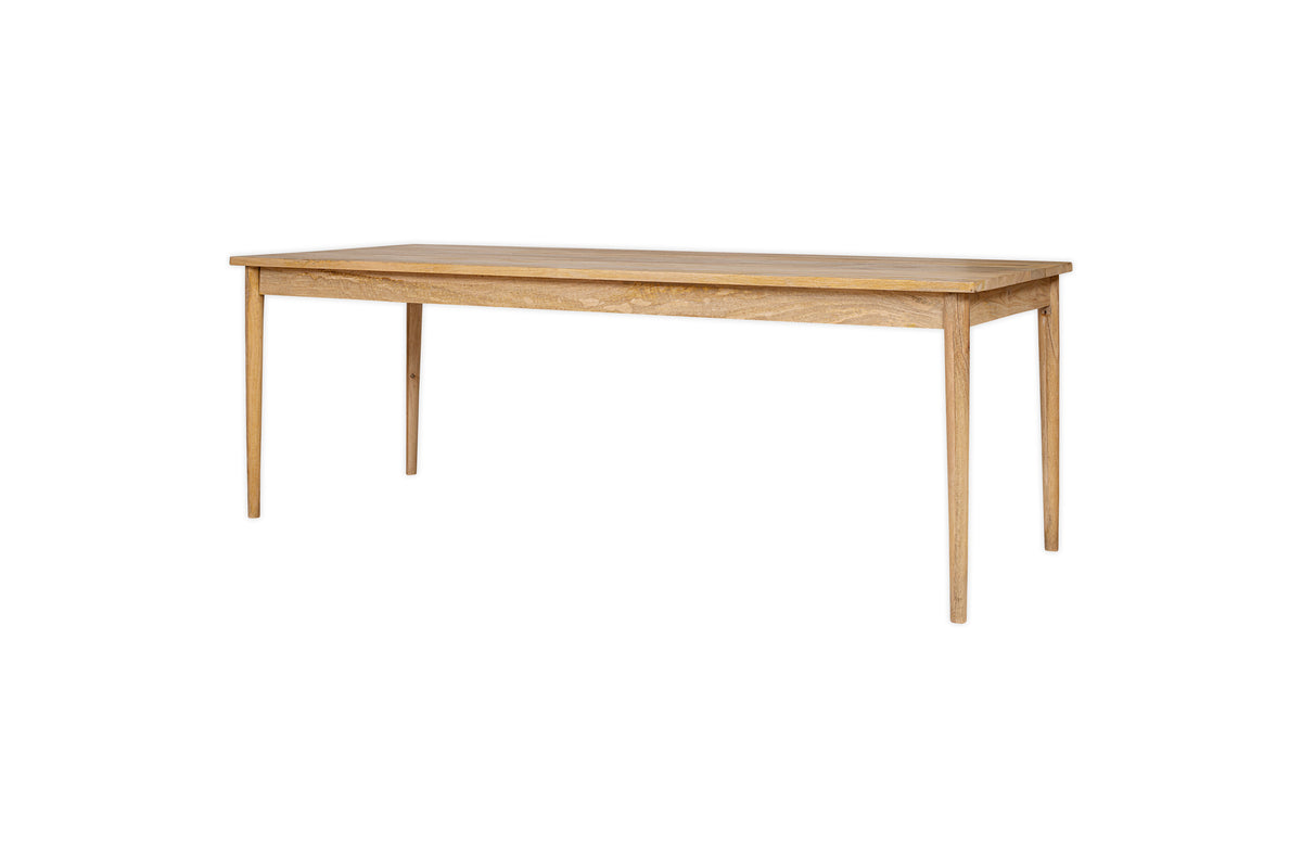 The Anbu Mango Dining Table - Natural by nkuku features a simple rectangular design with four straight legs and a light natural mango wood finish, shown against a white background. It brings subtle elegance to any space and complements the Anbu collection.
