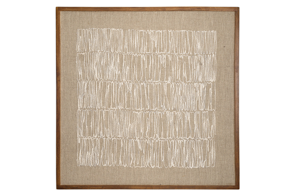 The Birala Hand Stitched Wall Art - Natural by nkuku features irregular vertical white stitching on textured beige fabric, framed in sustainable mango wood with a medium brown finish that enhances its neutral tones.