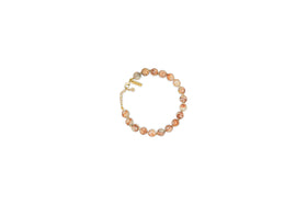 The nkuku Cerita Bracelet - Rhodochrosite showcases round marbled pink and beige stones, strung together with a gold chain extender and clasp. Presented on a plain white background, it’s a versatile accessory.