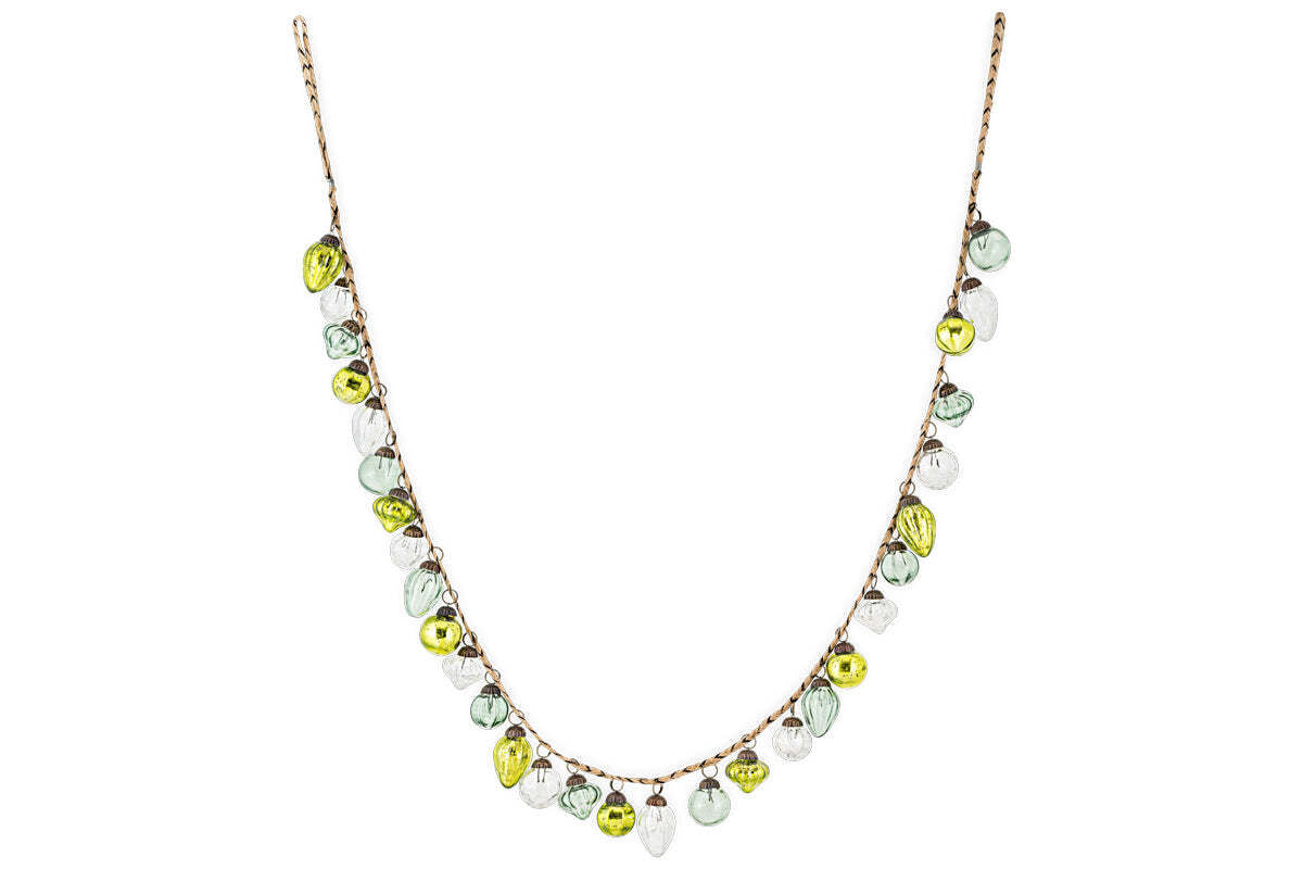 The nkuku Ekiti Bauble Garland - Mixed Green & Clear features a delicate brown chain with evenly spaced recycled glass beads in teardrop shapes of green, white, and yellow, forming a playful U-shape necklace.