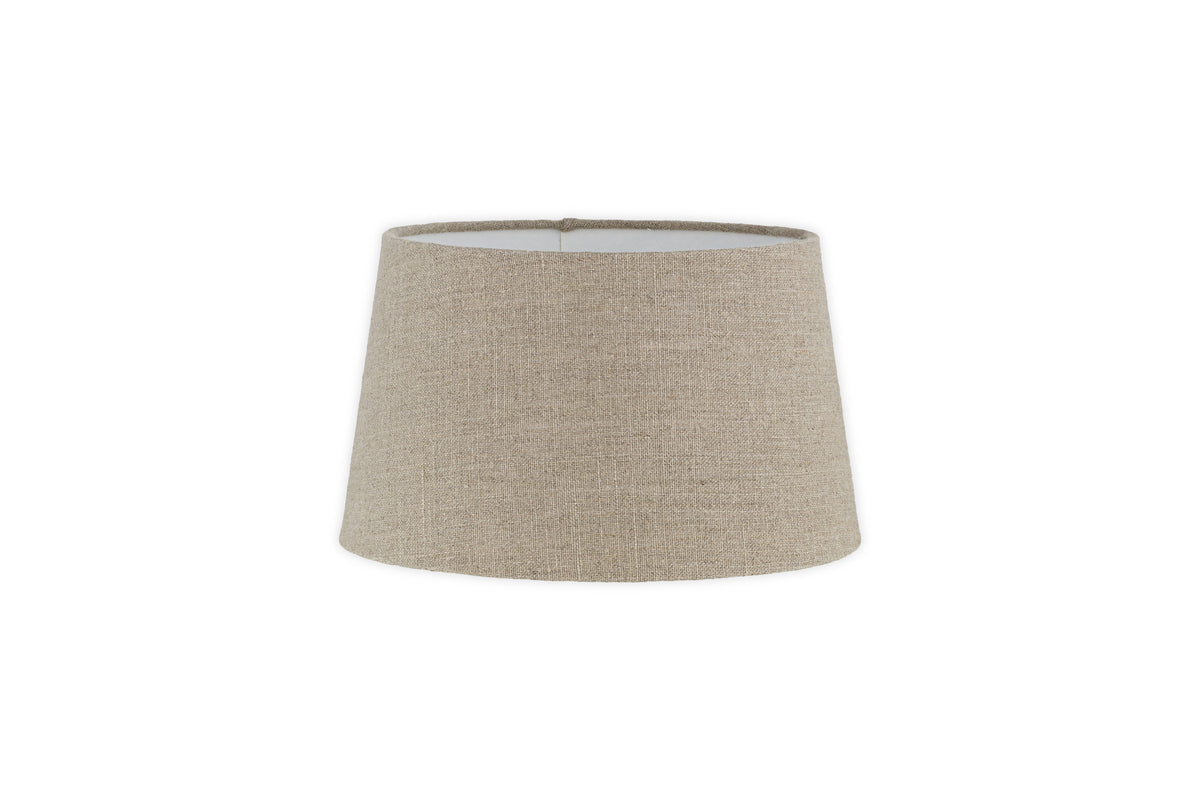The Embaata Linen Lampshade by nkuku features a natural, textured linen design in beige with a subtly flared cylindrical shape, shown against a plain white background.