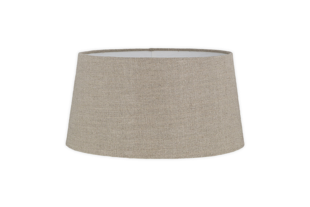 The Embaata Linen Lampshade - Natural by nkuku features a slightly tapered cylindrical shape and subtle textured linen finish in beige, shown against a white background.