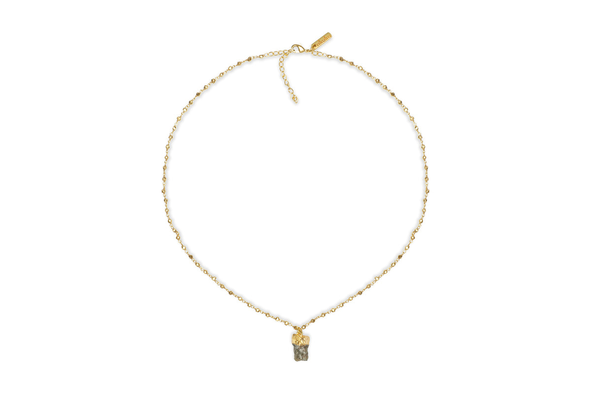 The Hadari Labradorite Necklace by nkuku features an irregular gray labradorite stone pendant on a delicate gold chain, showcased against a white background.