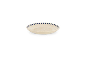 The nkuku Indigo Drop Garlic Grater in Cream & Indigo is a shallow, round beige ceramic plate with a textured center and hand-painted dark blue triangle accents around the rim, perfect for grating garlic.