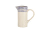The Indigo Drop Jug - Cream & Indigo - Small by nkuku is a cream-colored ceramic milk jug with a curved handle and narrow spout, featuring blue teardrop motifs around the rim—ideal contemporary serveware for your table.