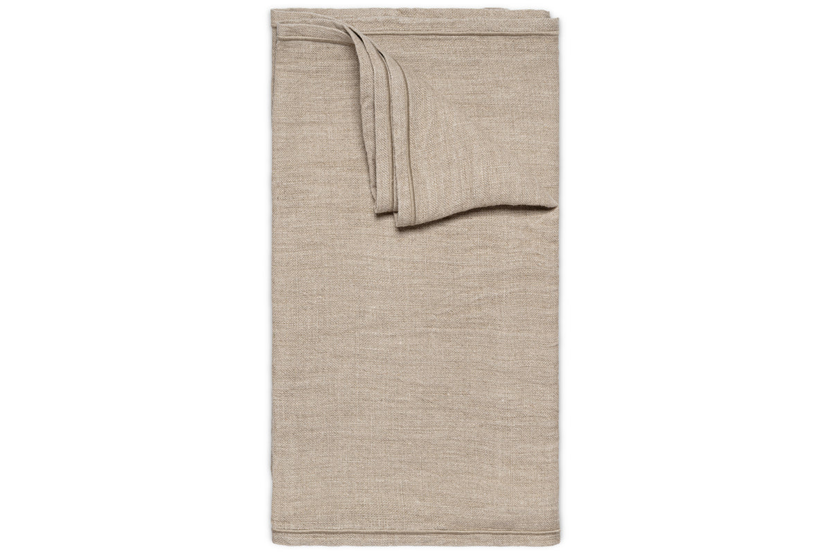 The Junto Linen Runner- Natural - Large by nkuku is displayed on a white background. Its smooth, beige linen finish and crisp edges add elegance and harmony to any table setting.