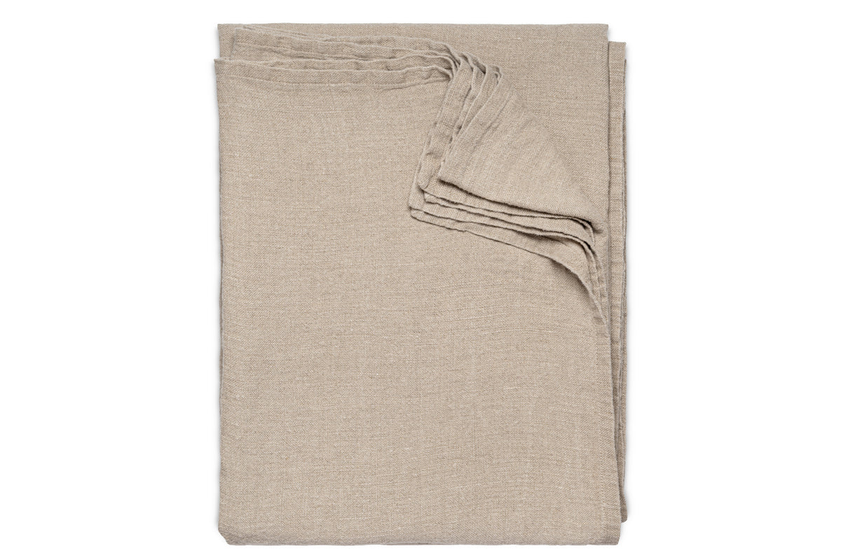 The nkuku Junto Linen Tablecloth in Natural (Large) is neatly folded and arranged on a white background.