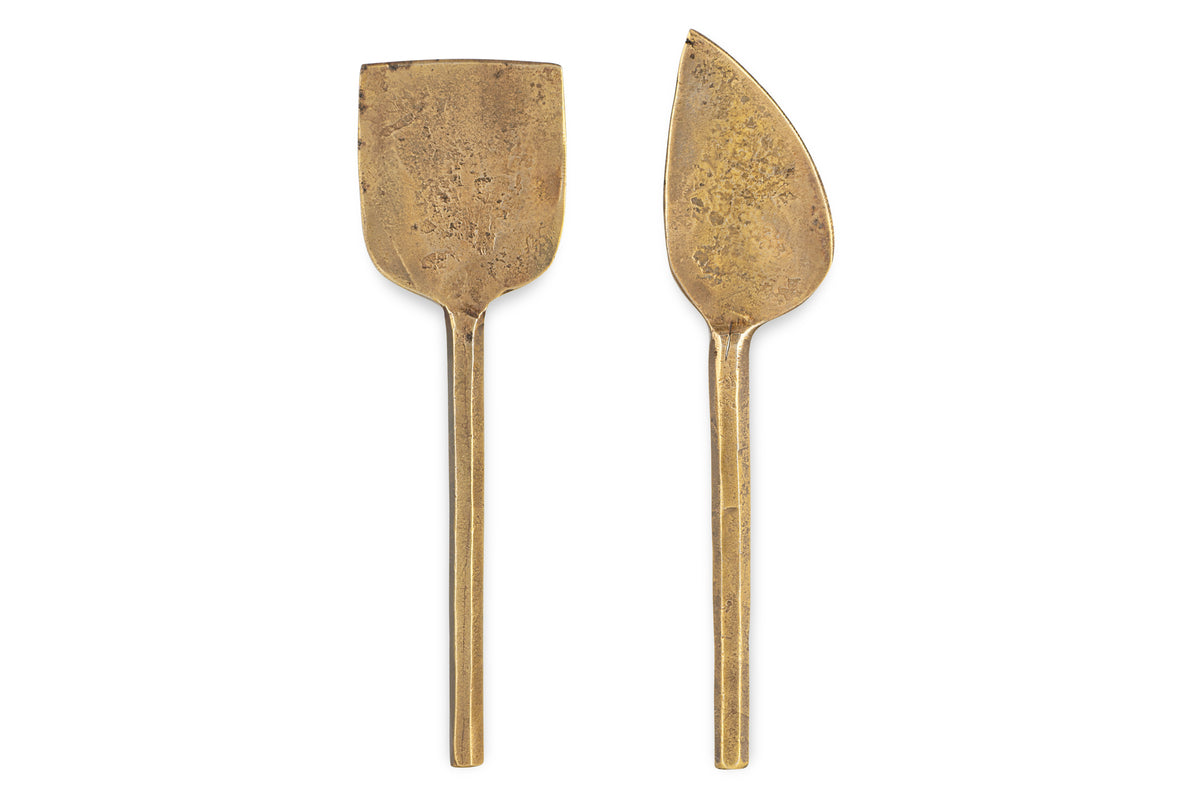 The nkuku Kasa Cheese Knives - Antique Brass (Set of 2) features simple handles and two distinct blades, perfect side by side on a white background to elevate your cheese board.